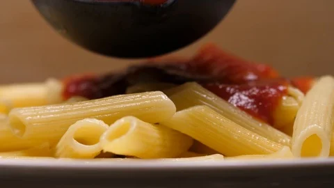 Macro close up of red sauce added to penne pasta noodles in 4k. Stock Footage 86536397