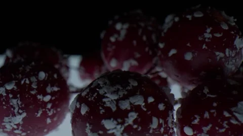 Macro close up of red spherical objects with white flakes slowly spinning in Stock Footage 326301784