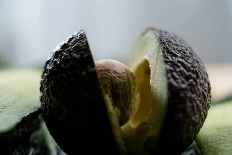 Macro close up of ripe avocado split open with seed exposed, revealing dark Stock Photos