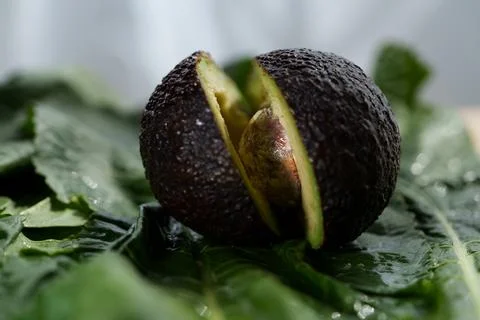 Macro close up of ripe avocado split open with seed exposed, revealing dark Stock Photos