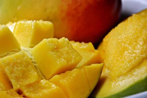 Macro close-up of a ripe mango hanging from a leafy tree branch, with dewdr.. Stock Photos