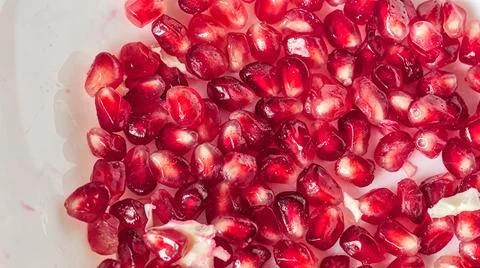 Macro Close-up of Scattered Bright Ruby Red Pomegranate Arils (Seeds) on a White Stockfoto's
