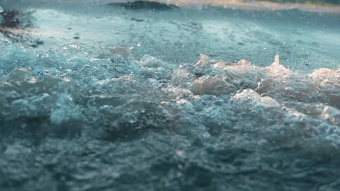 Macro close-up shot of gentle ocean waves splashing and foaming over golden Stock Footage 346420697