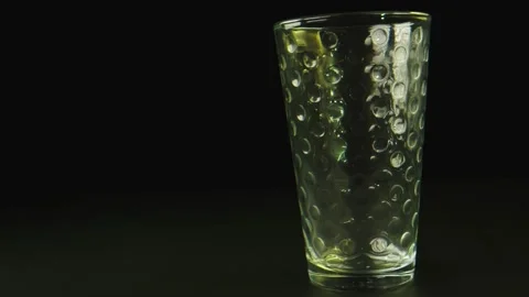 Macro close-up shot of ice falling on a glass. Background is black. Stock Footage 131689858