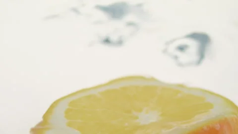 Macro close up of a slice of Orange  splashing in water in slow motion Stock Footage 273121813