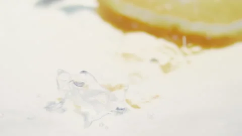 Macro close up of a slice of Orange  splashing in water in slow motion Stock Footage 273121814