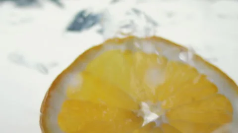 Macro close up of a slice of Orange  splashing in water in slow motion Stock Footage 273121815