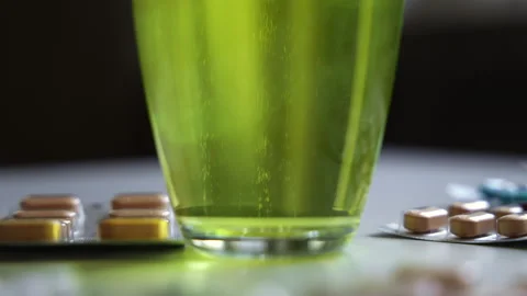 Macro close up of a soluble effervescent tablet dissolving in a glass of greenis Stock Footage 341827494