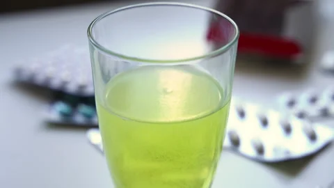 Macro close up of a soluble effervescent tablet dissolving in a glass of greenis Stock Footage 341828175