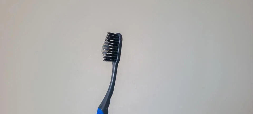 Macro close-up of a toothbrush with toothpaste on black bristles against a .. Fotos Stock