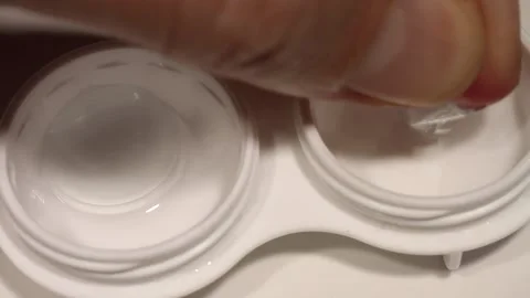 Macro close up Top down contact lenses put into container and solution added Stock Footage 164845731