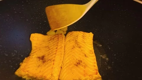Macro close-up view of fresh hot sizzling fried salmon cooked in a dark fry.. Video stock 318254408