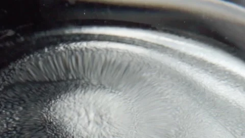 Macro close up of water drop falling onto liquid surface creating ripple and Stock Footage 340799786