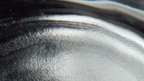 Macro close-up of water drop falling onto liquid surface creating circular Stock Footage 343709510