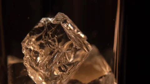 Macro close up of  Whiskey being poured onto Ice cubes in glass of whisky Stock Footage 128576945
