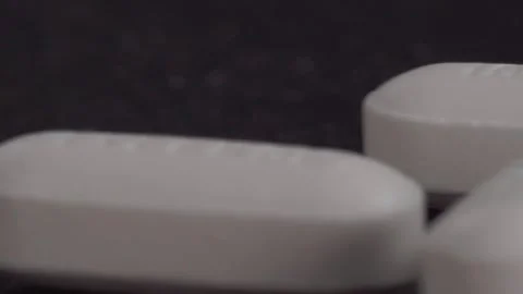 Macro Close Up of White Pharmaceutical Tablets on Dark Surface Stock Footage 342236197