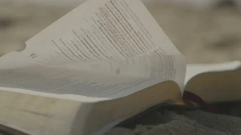 Macro Close up of Wind Turning Pages of Holy Bible on Sandy Beach on sunny day Video stock 211881347