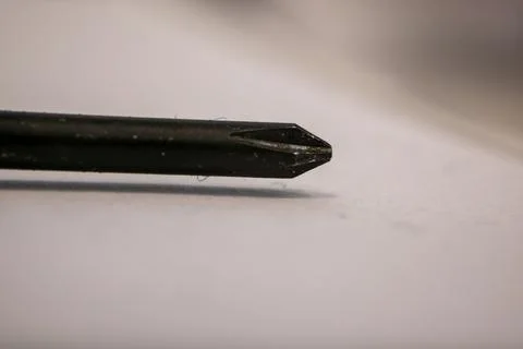 A macro close-up of a worn black screwdriver tip resting on a light surface. Stock Photos