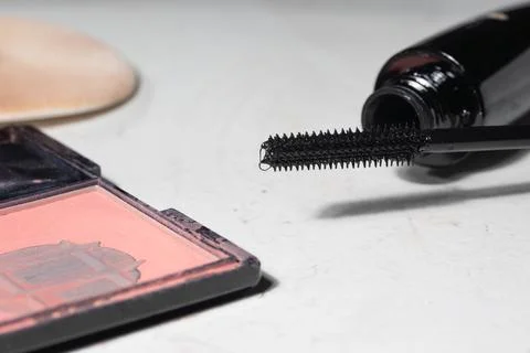 Macro close-up of worn makeup items on a light surface: mascara wand extended Stock Photos
