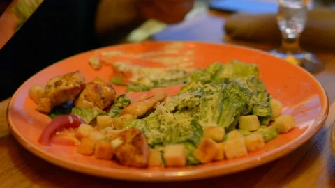 Macro closeup of caesar salad on plate with red tongs, parmesan cheese, dressing Stock Footage 97830399