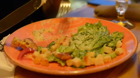 Macro closeup of caesar salad on plate with red tongs, parmesan cheese, dressing Stock Footage 97833858