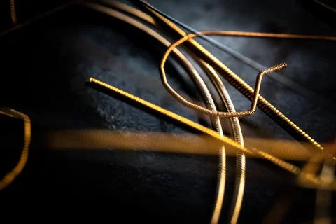 Macro Closeup of Cut End of Bronze Acoustic Guitar String Laying on Used Stri Foto stock