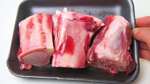Macro closeup hand holding beef cow marrow bones with meat Stock Footage 194156725