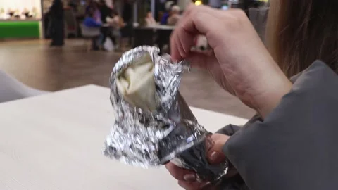 Macro closeup of hand holding, opening unwrapping chicken roll 스톡 동영상 220450439