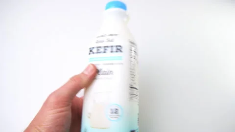 Macro closeup hand holding Trader Joe's low fat plain unsweetened kefir drink Video stock 194158102