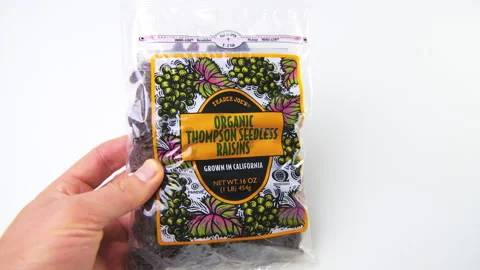 Macro closeup hand holding Trader Joe's seedless organic Thompson raisins Stock Footage 194158864