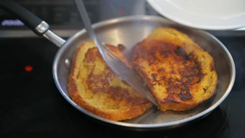 Macro closeup of hand putting brioche french toast from frying pan to plate Stock Footage 154184352