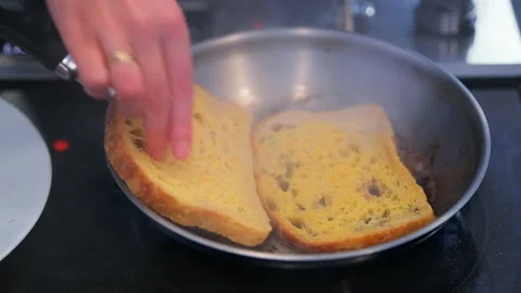 Macro closeup of hand putting brioche french toasts to frying pan Stock Footage 154184370