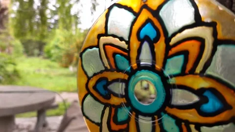 Macro closeup of hanging glass mobile spinning by the wind in the backyard of Stock Footage 130970361