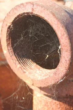Macro closeup of large old rusted metal industrial pipe with cobwebs Stock Photos