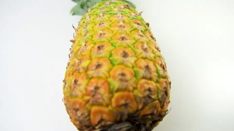Macro closeup of one ripen raw unpeeled pineapple fruit on white background Stock Footage 179546364