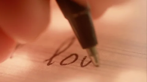 Macro closeup: A pen writes "I love" on lined paper. Pink hue. Stock Footage 91875606