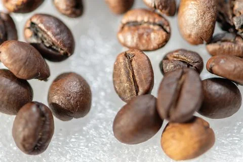 Macro closeup of roasted coffee beans scattered on white background 스톡 사진