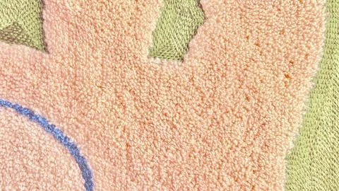 Macro closeup of soft peach tufted rug texture with green accents and blue st Stock Photos