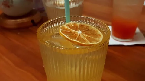Macro Closeup Vibrant Citrus Orange Lemon Drink with Ice and Dried Slice Stock Footage 319825233