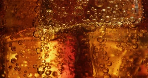 Macro of Cola Bubbles and Ice Cubes in a Glass Shot on Red Vidéo 123977278