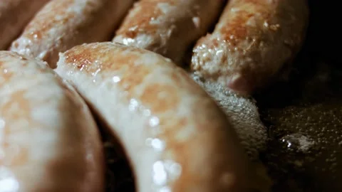 Macro of cooking sausages in black pan with oil. Frying sausages in hot Stock Footage 144322550