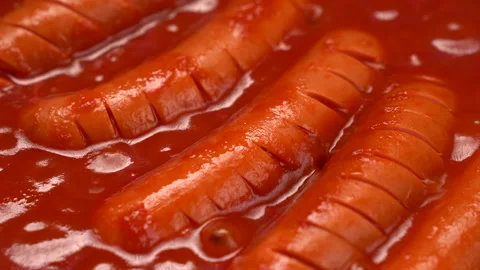 Macro cooking sausages in boiling red tomato sauce 4K. Boiling sausages in red 動画素材 197431964