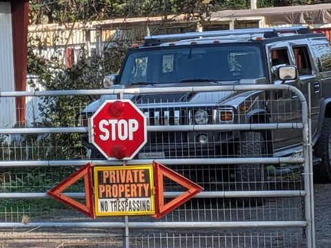Macro of a creative gate sign featuring "Stop" and "No Trespassing" markers Stock Photos