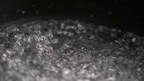 MACRO, DOF: Tiny drops of water come flying out of the pan of boiling water Stock Footage 103186927