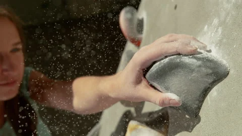 MACRO, DOF: Tiny particles of chalk fly in air as climber grips a grey hold. Stock Footage 135276700