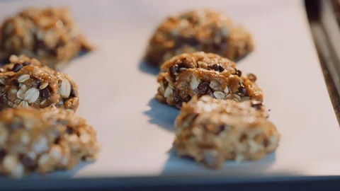 Macro dolly across several chocolate chip oatmeal cookies in oven before baking Stock-Footage 129292665