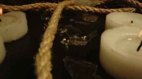 Macro dolly out of a long rope running between burning candles and broken glass Stock Footage 336004473