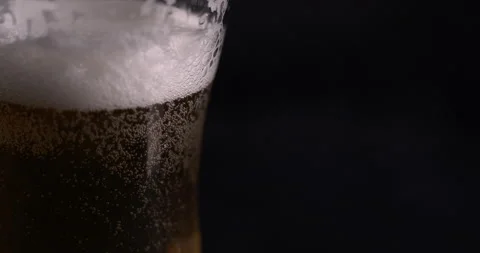 Macro drop flows down a glass with beer on a black background Stock Footage 130359630