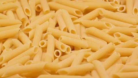 Macro of the dry Penne pasta on a rotating stand in UHD Video stock 99181308
