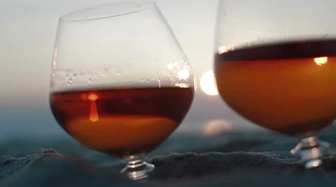Macro extra close up of two glasses of brandy on the sand over incredible beach Stock Footage 49987374